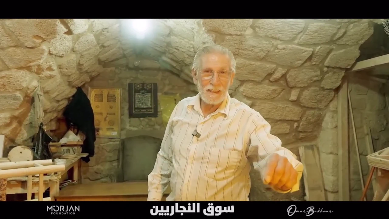 Older maker standing inside a stone workshop in Souk Al-Najjarin