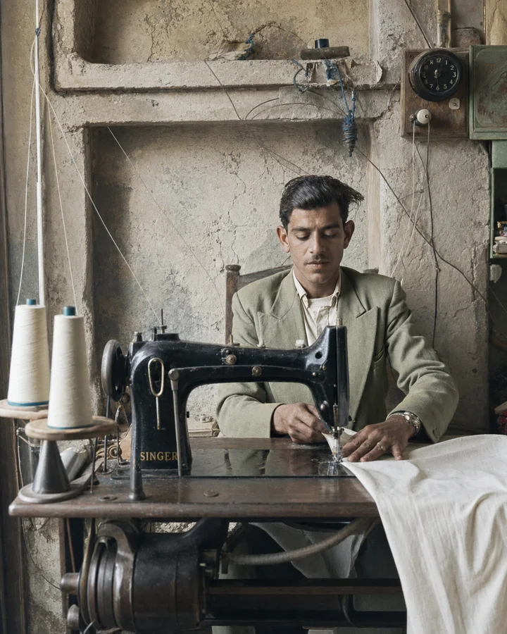 Young Old Sidon tailor working at a black sewing machine in a limestone workshop